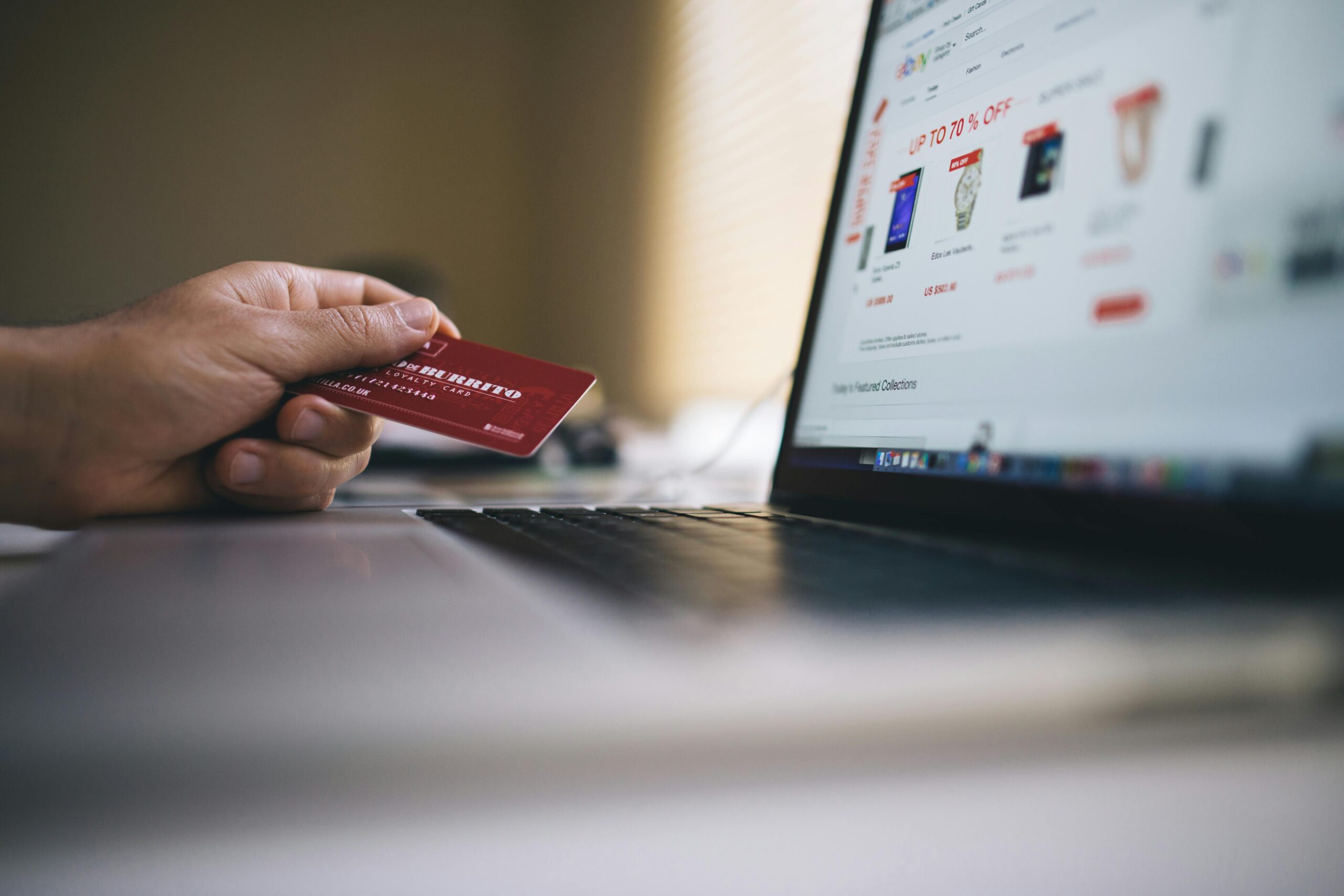 Person holding a credit card while shopping online on a laptop, indicating ecommerce transactions.